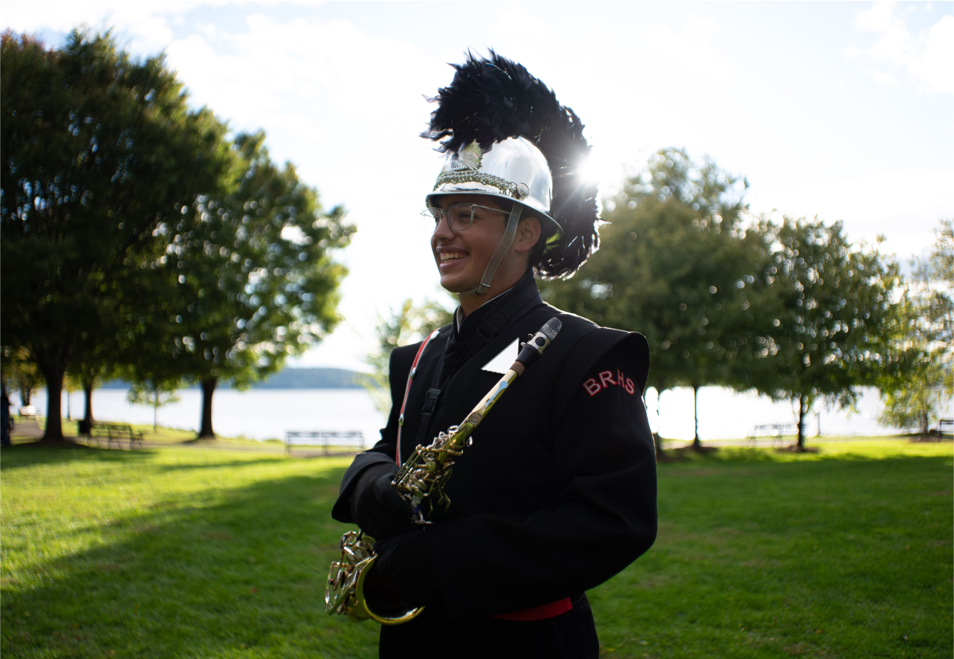 Diego Catalan dressed in his marching band uniform looks to the left as the sun sets behind him.